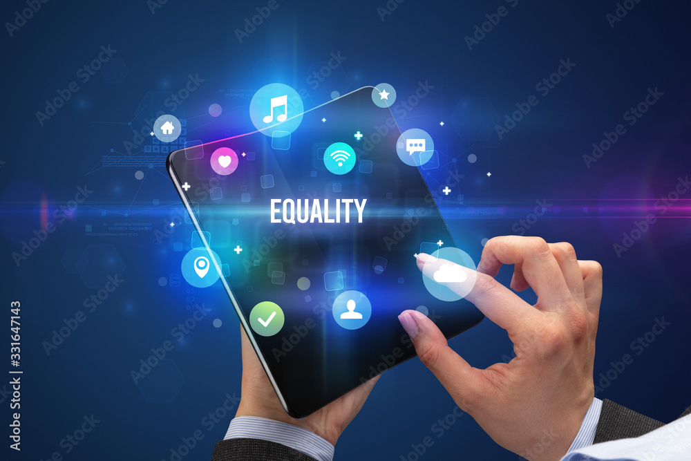 Businessman holding a foldable smartphone with EQUALITY inscription, social media concept Businessman holding a foldable smartphone with EQUALITY inscription, social media concept