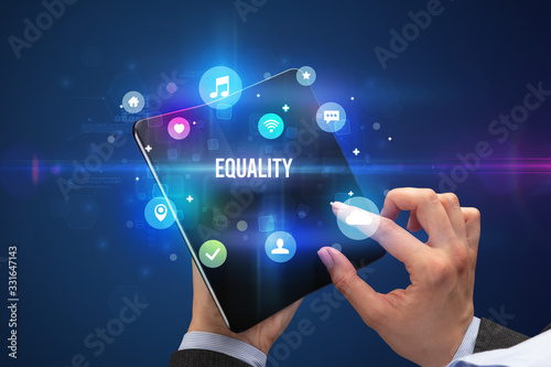 Businessman holding a foldable smartphone with EQUALITY inscription, social media concept