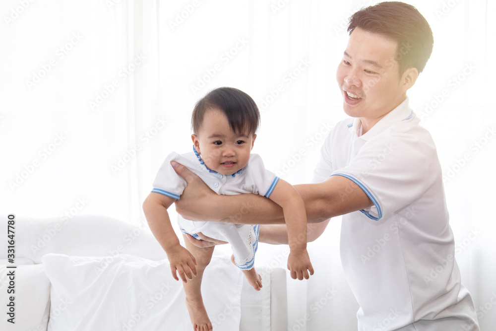 Asian young family help together feeding adorable cute girl at home, father playing with daughter hold her to fly on bed, mother pregnancy looking beloved husband and daughter multi task concept Asian young family help together feeding adorable cute girl at home, father playing with daughter hold her to fly on bed, mother pregnancy looking beloved husband and daughter multi task concept