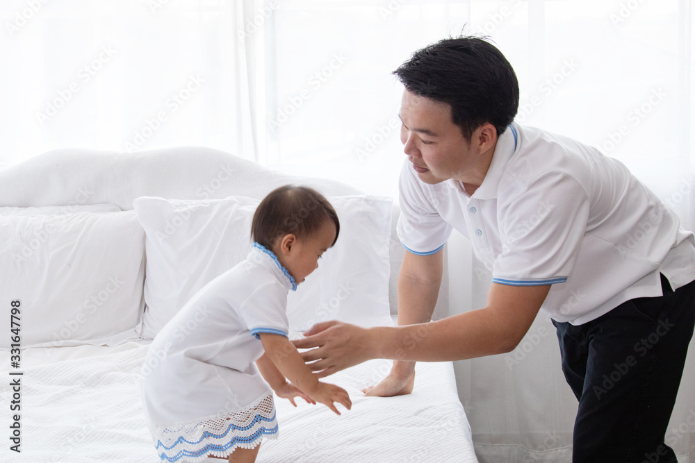 Asian young family help together feeding adorable cute girl at home, father playing with daughter hold her to fly on bed, mother pregnancy looking beloved husband and daughter multi task concept Asian young family help together feeding adorable cute girl at home, father playing with daughter hold her to fly on bed, mother pregnancy looking beloved husband and daughter multi task concept