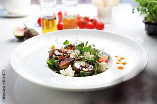 Salad with figs and goat cheese. A plate with an appetizing dish. Application suggestion. Culinary photography, food stylization.