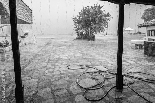 Fotografie Black and white photography of heavy rainstorm pouring outdoors at empty  beach of hotel resort in Greece