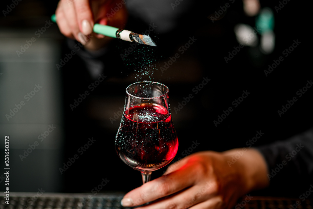 barman's hand decorates alcoholic cocktail with colored powder using brush. - obrazy, fototapety, plakaty 