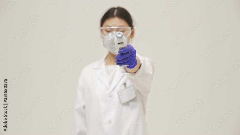 Young asian negative doctor woman isolated over white wall background in sterile uniform measure temperature with contactless thermometer Young asian negative doctor woman isolated over white wall background in sterile uniform measure temperature with contactless thermometer