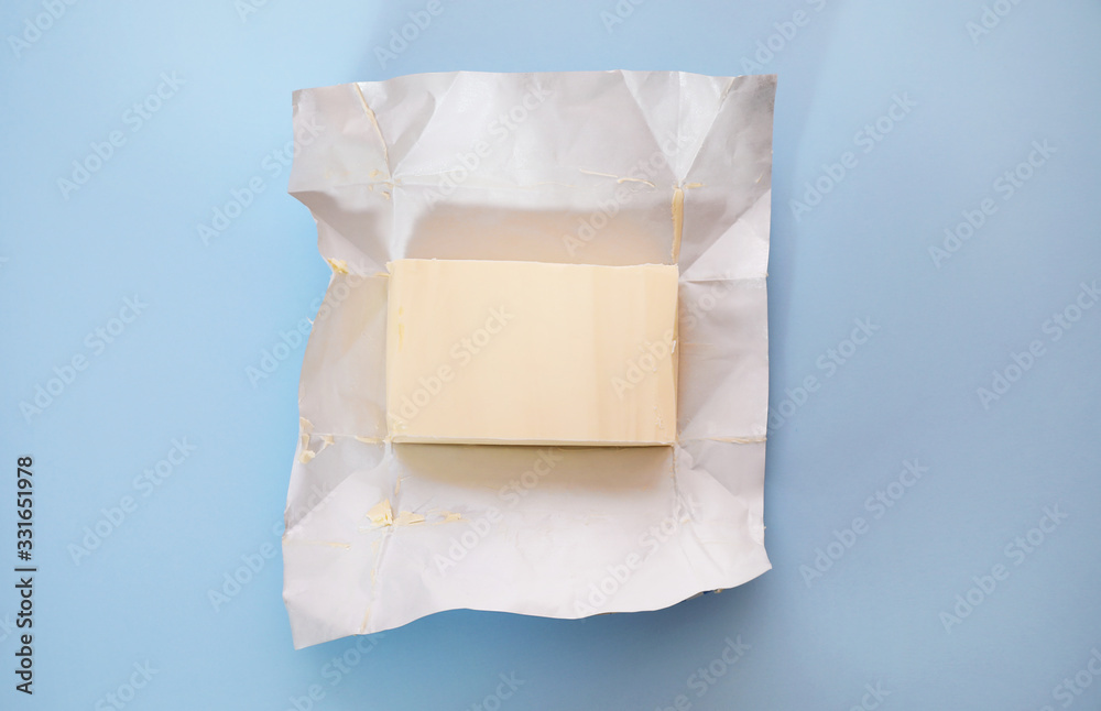 Piece of butter on blue background, top view - obrazy, fototapety, plakaty 