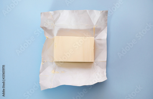 Piece of butter on blue background, top view