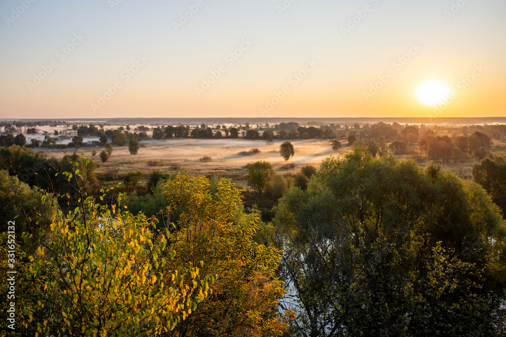 Amazing perfect morning foggy landscape in scenic countryside of Ukraine. Aerial vista view at horizon line, meadows, green forests and dark long shadows of sunrise sun seen on misty ground.