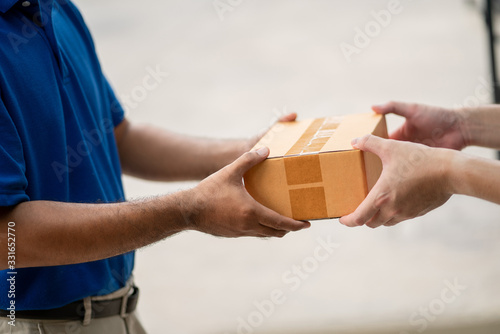 Hand accepting a delivery of boxes parcel cardboard from deliveryman. Messenger and delivery concept.
