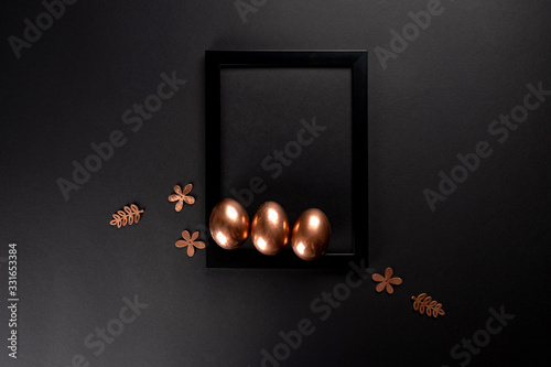 Easter background with black fhoto frame and gold Easter eggs on black background. Flat lay, Top view, mockup, copy space. photo