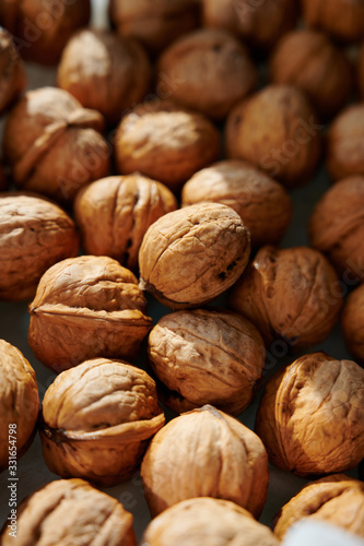Whole walnuts, vertical close-up shot in harsh sunlight.
