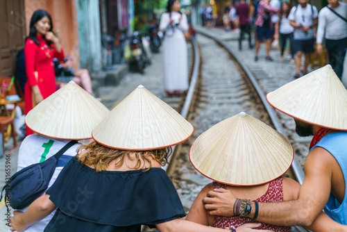 Foreign tourists with Vietnamese conical hats taking photo at narrow train railroad in old town in Hanoi © Hanoi Photography