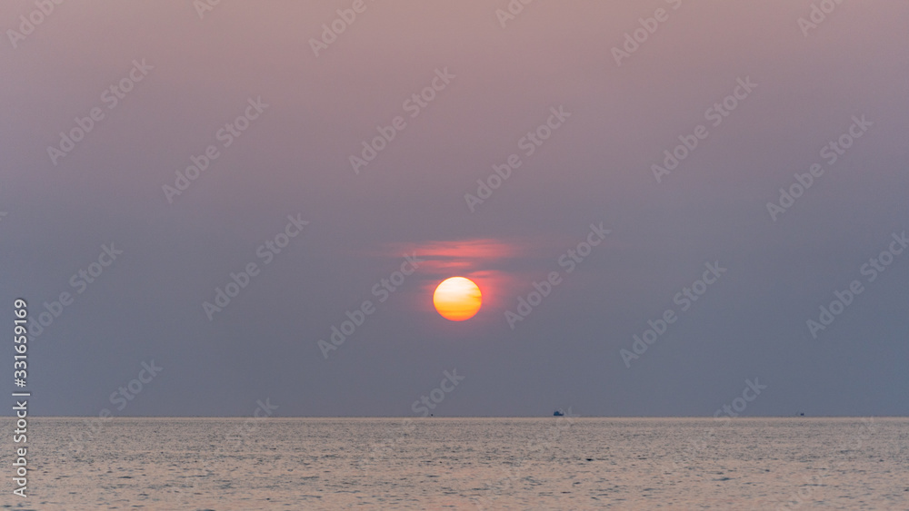 Amazing pink to purple sunset with orange sun over a tropical ocean