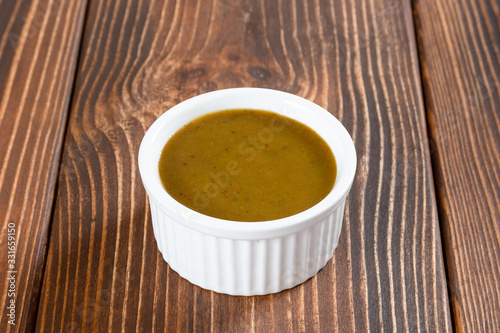 White ceramic sauce-boat of georgian sauce green tkemali on wooden table