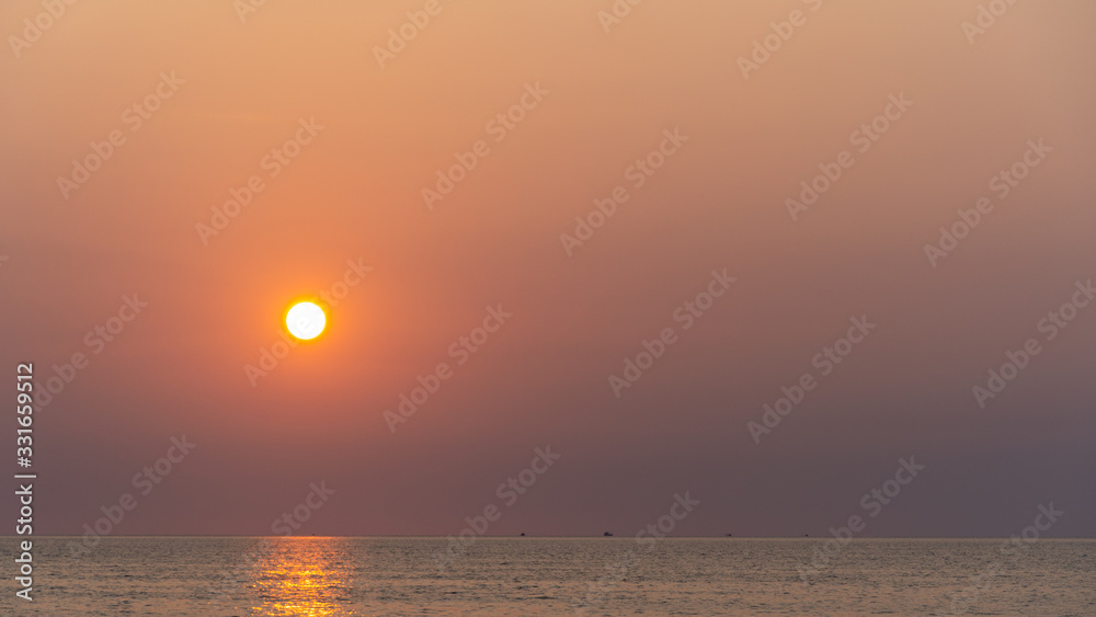 Amazing orange to purple sunset with yellow sun over a tropical ocean