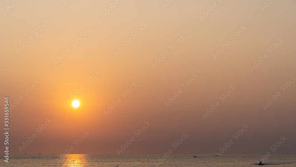 Amazing orange to purple sunset with yellow sun over a tropical ocean