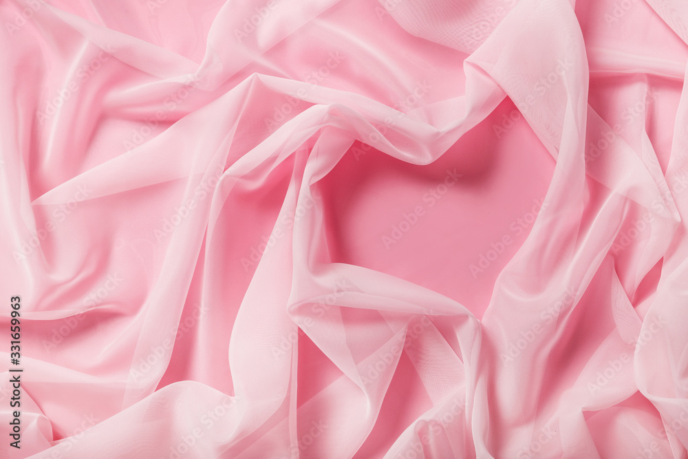 Tender pink silk fabric draped in shape of heart in pink background