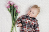 Cute little boy in a plaid shirt holds a bouquet of pink tulips