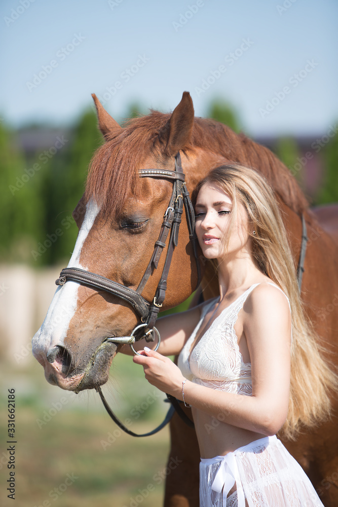 Obraz premium Beautiful young woman hugs a horse on nature
