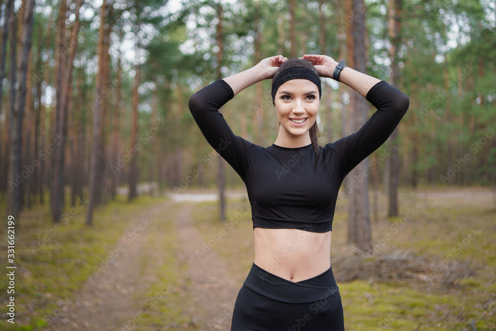 Young woman doing warm-up before running in forest. A teenager prepares to run on forest paths. Natural forest light. Young woman doing warm-up before running in forest. A teenager prepares to run on forest paths. Natural forest light.