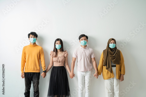 people with face masks hold hand supporting each other. fights against the virus