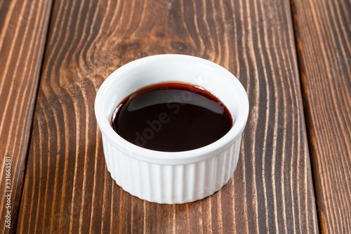White ceramic sauce-boat of soy sauce on a table
