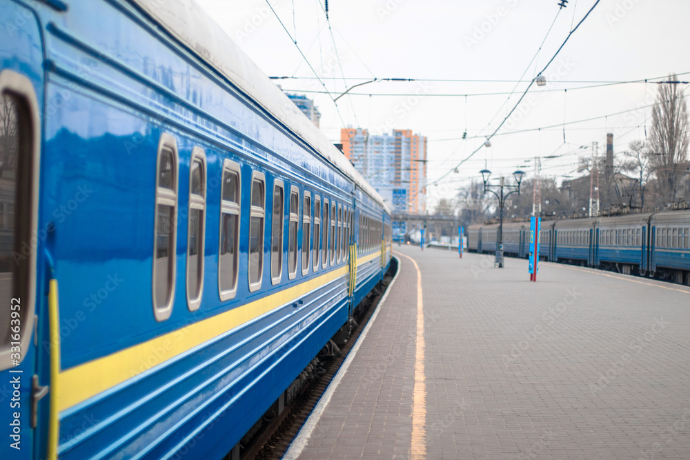 Close of the blue metal railway carriages with clean windows stand on the platform of the train station. Departure or arrival of a train. Travel concept