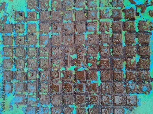 texture of a metal manhole from a well with peeling turquoise paint after rain