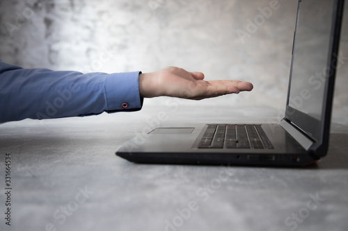 Otwarta dłoń przed monitorem laptopa na betonowym tle