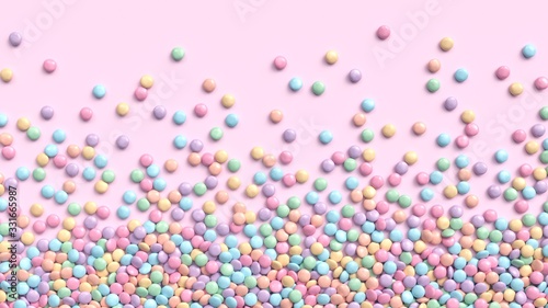 Colorful coated chocolate candies in pastel tones scattered on pink background
