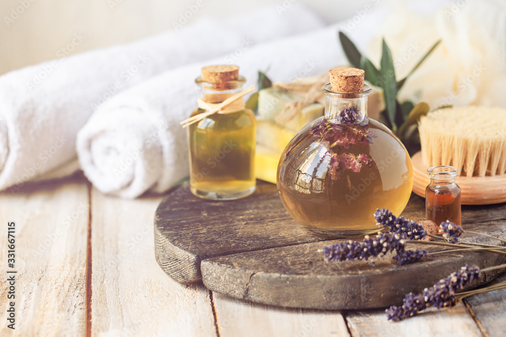 Concept of natural organic oil in cosmetology. Moisturizing skin care, aromatherapy. Gentle body treatment. Atmosphere of harmony relax. Wooden background, lavender flower, wooden brush. Copy space