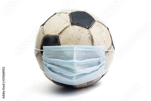 old battered shabby soccer ball with medical mask coronavirus covid 2019 euro 2020 on a white background isolate