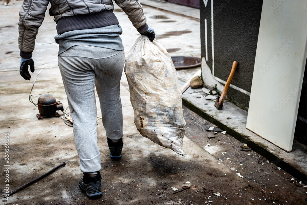 A woman takes out garbage in a bag. Cleaning the area from garbage in the yard outdoor. A woman takes out garbage in a bag. Cleaning the area from garbage in the yard outdoor.