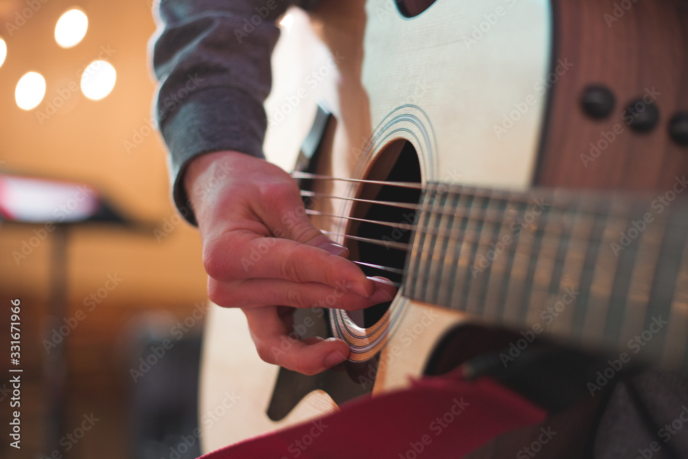 Fototapeta premium Young man playing on acoustic guitar
