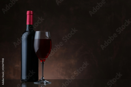 Wine bottle and glass of red wine on brown background