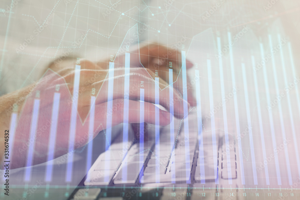 Double exposure of graph with man typing on computer in office on background. Concept of hard work. Closeup.
