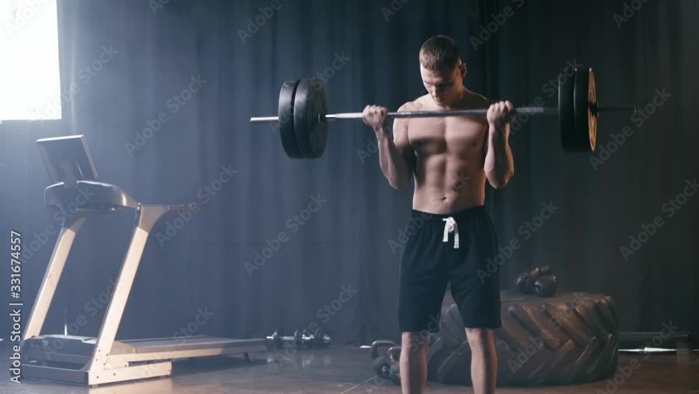 muscular man working out with barbell in gym 