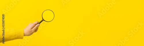 magnifier in hand over yellow background, panoramic mock-up image