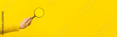 Foto magnifier in hand  over yellow background, panoramic mock-up image
