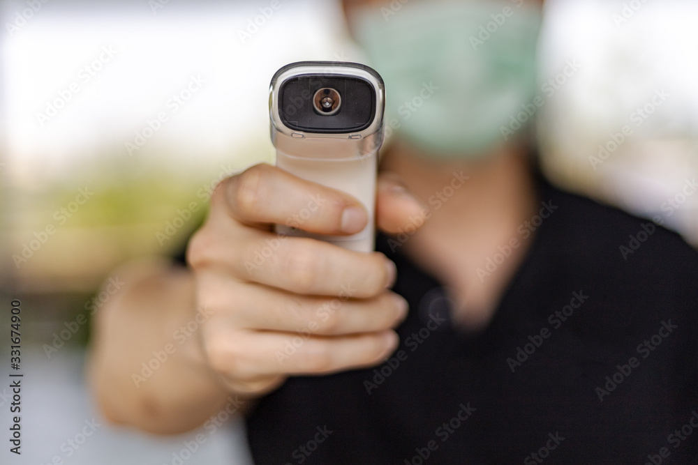 A staff is holding thermo scan to check temperature for any CORONA Virus suspect A staff is holding thermo scan to check temperature for any CORONA Virus suspect