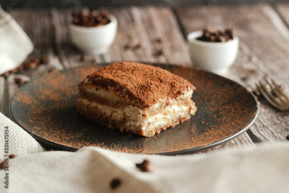 Fototapeta premium Tiramisu cake on a plate. Romantic composition with coffee and other elements
