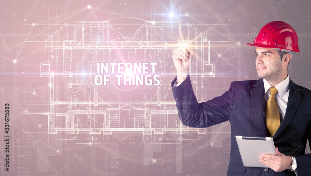 Handsome architect with helmet drawing INTERNET OF THINGS inscription, new technology concept Handsome architect with helmet drawing INTERNET OF THINGS inscription, new technology concept
