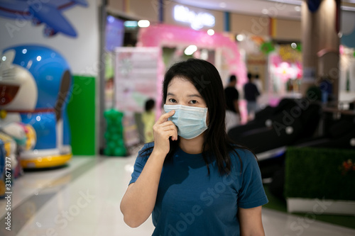 Asian woman wearing surgical mask protection walking in shoping mall.