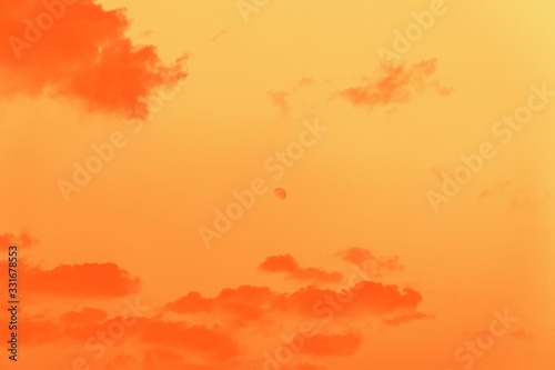 Moon behind the clouds, orange gradient toned