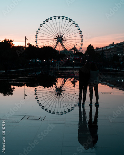 silhouette of ferris wheel at sunset or sunrise & water reflection photo