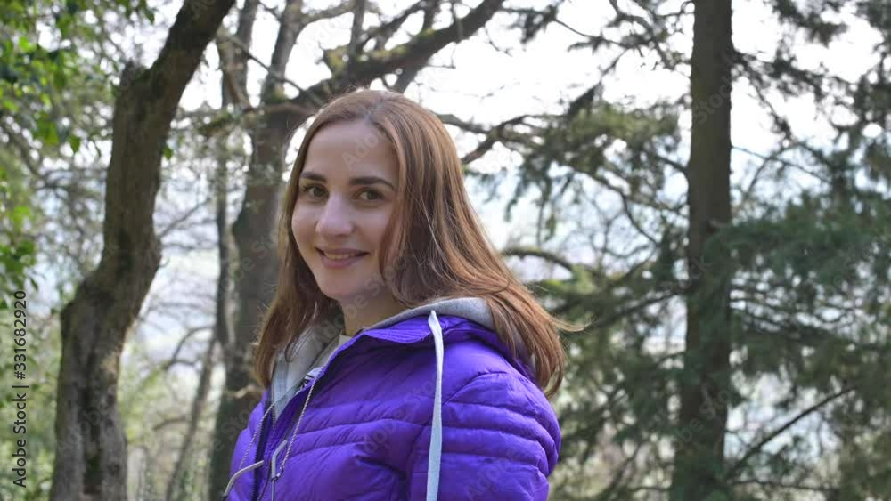 Girl in the park in spring. A young woman in a purple jacket and brown hair is smiling and happy. Girl in the park in spring. A young woman in a purple jacket and brown hair is smiling and happy.