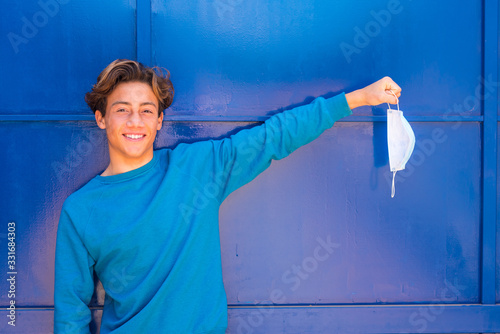 one happy young teenager with a blue background and wearing a blue sweater without medical mask after quarantine and after passed the coronavirus or covid-19 - no more mask and no more lockdown  photo