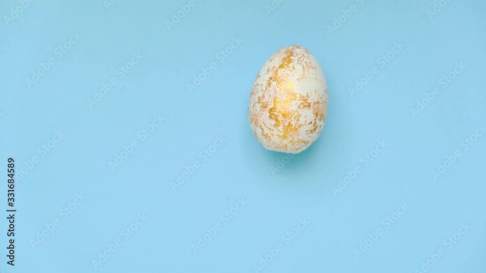 Easter egg are spinning turning on blue table. Egg trendy colored classic blue, white and golden . Happy Easter. Minimal style. Top view. Easter egg are spinning turning on blue table. Egg trendy colored classic blue, white and golden . Happy Easter. Minimal style. Top view.