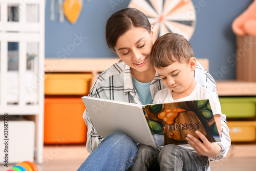 Nanny and cute little boy reading book at home