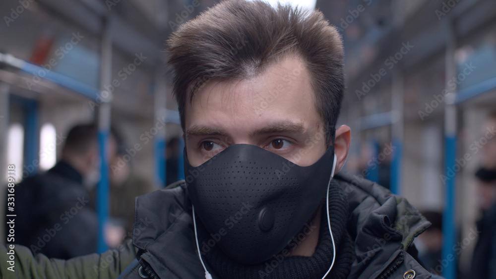 Close up portrait of a young man in a reusable protective mask in subway train. Coronavirus epidemic in big city. Safety life concept. COVID-19 pandemic