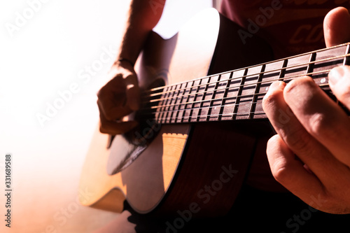 Young man's hands playing acoustic guitar, close up